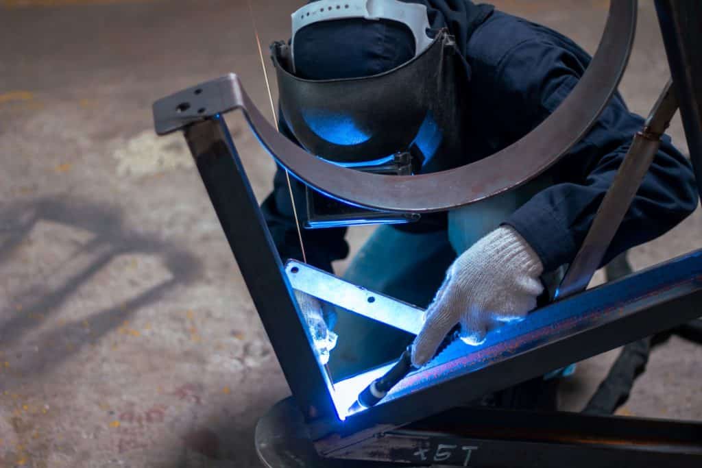 welder working on fabricating metal pipe stands