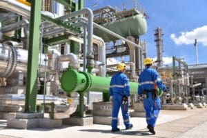 personnel walking through a refinery structure with piping, slug catchers, pressure vessels, etc.